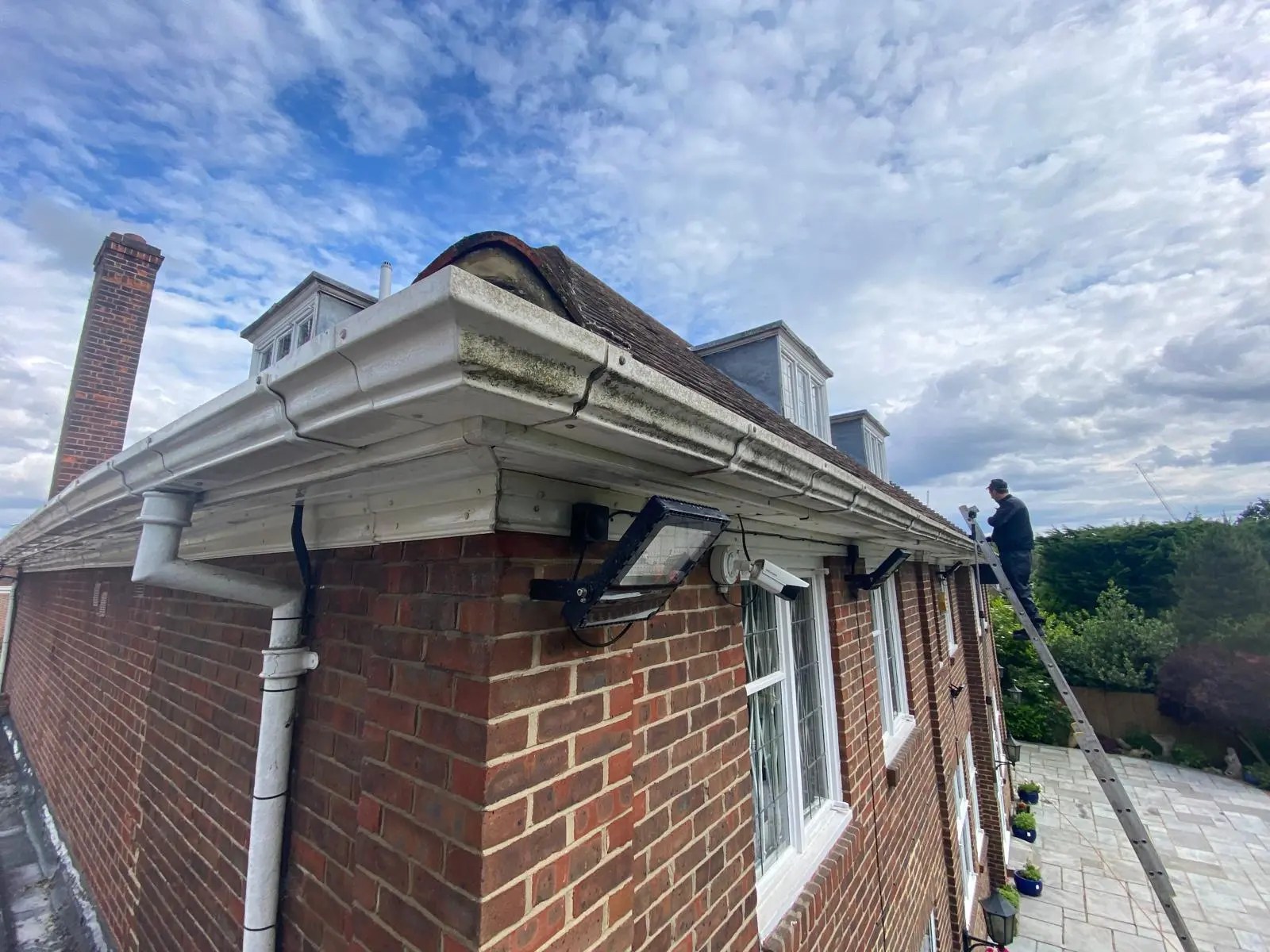 Diamond Gutters UK technician on a roof cleaning gutters