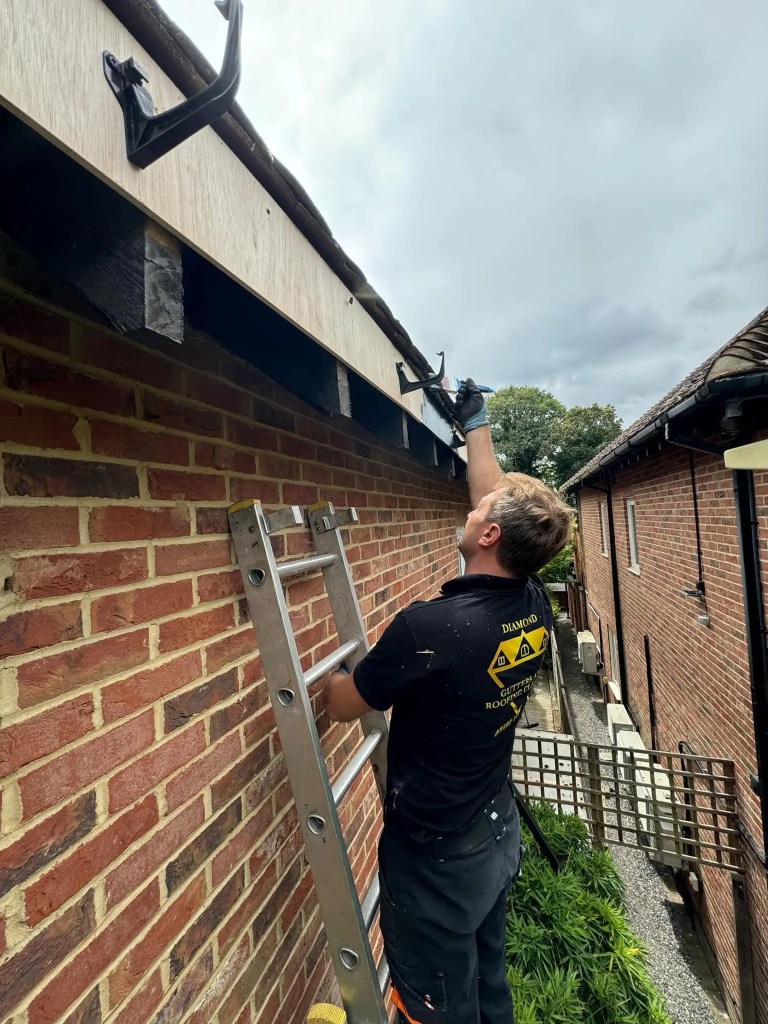 Diamond Gutters UK technician using a brush to clean and maintain gutters